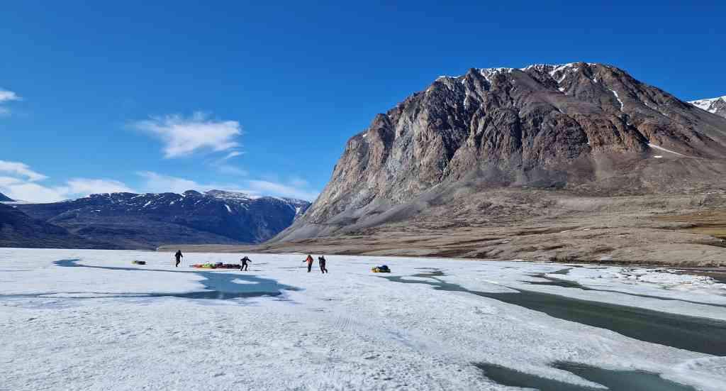 Trekking av pulker over delvis oppt&oslash;rket fjordis. Foto: Kunuk Lennert  