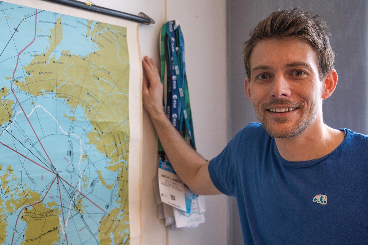 Portrett av ein blid mann som st&aring;r ved sida av eit kart over Nordpolen.