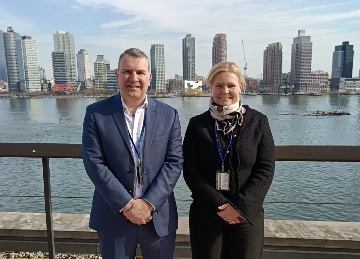 The two are posing with New York in the background.