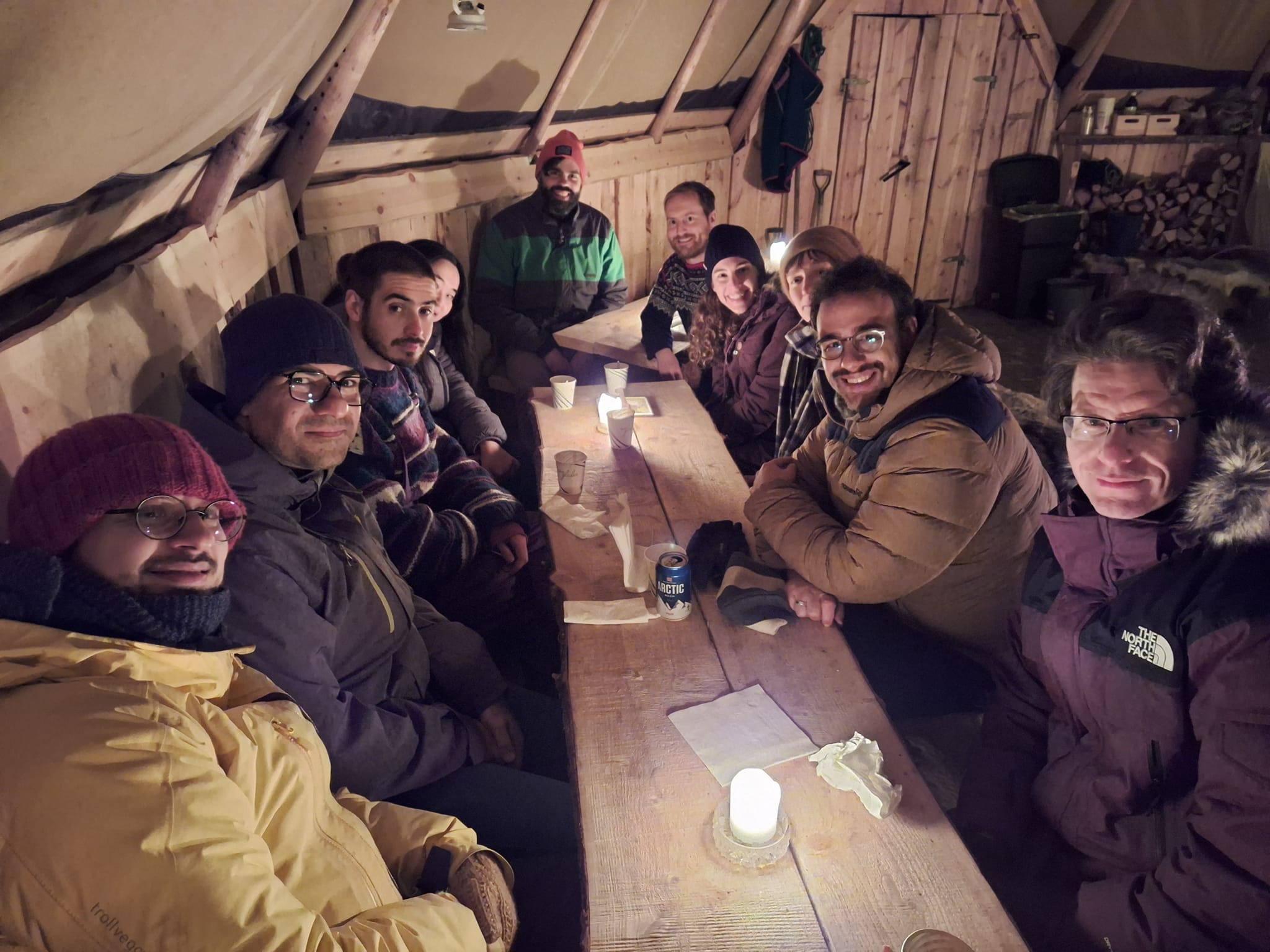 Several people are sitting around a table in a big tent.