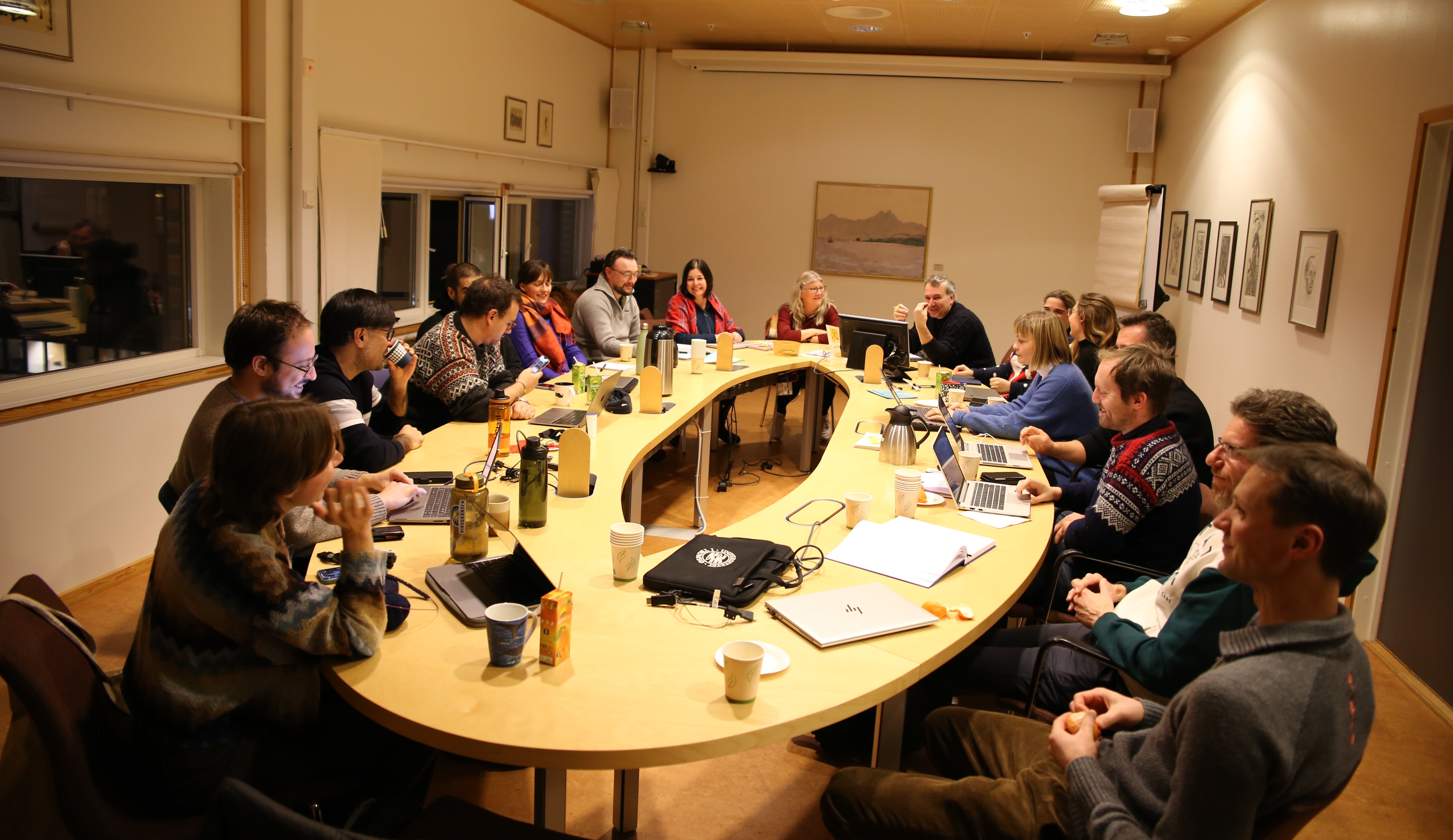 20 people sitting around a table talking and laughing