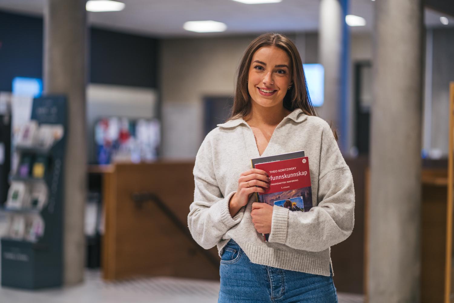 Student som holder opp en bok.