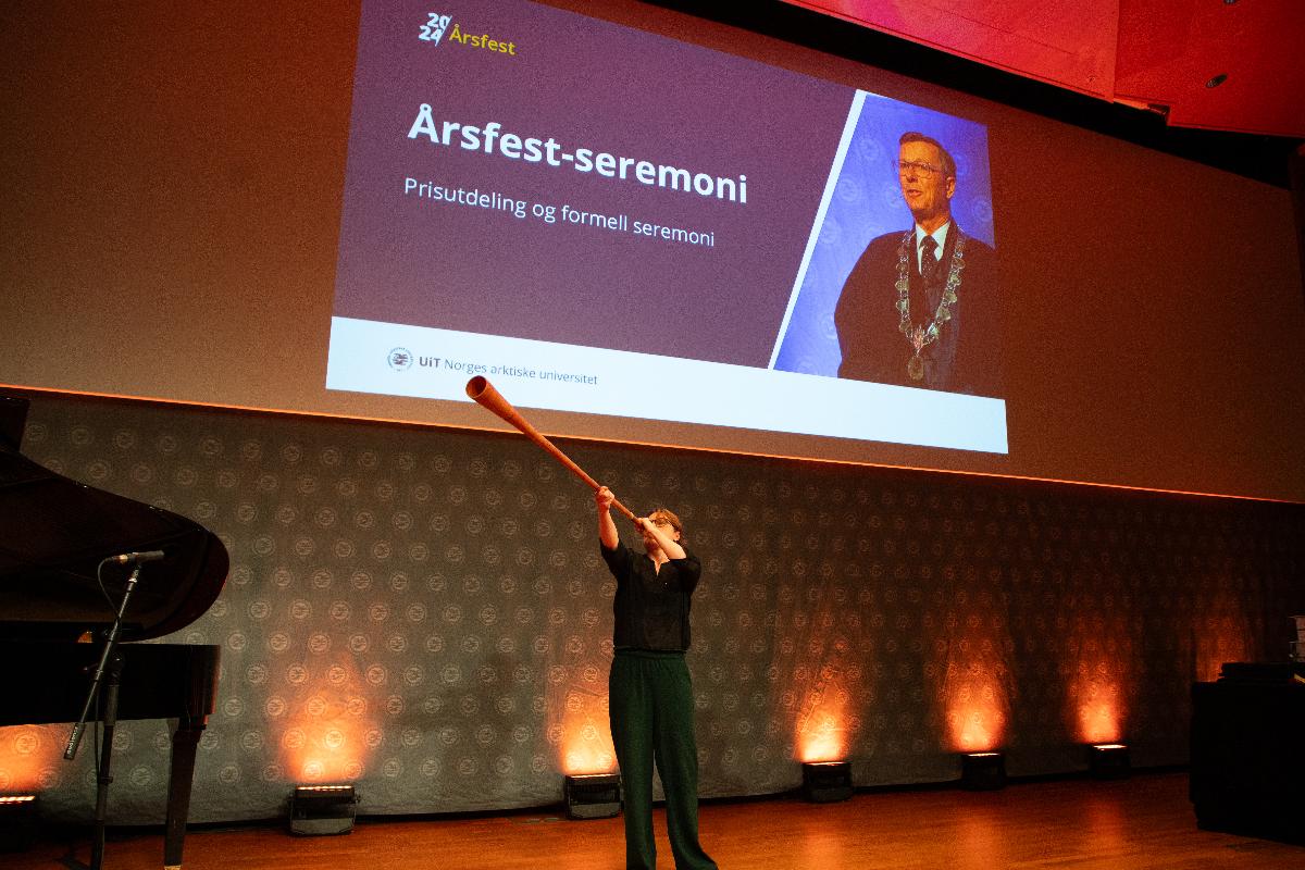 Fl&oslash;ytespiller p&aring; podium f&oslash;r prisutdeling p&aring; et universitet. 