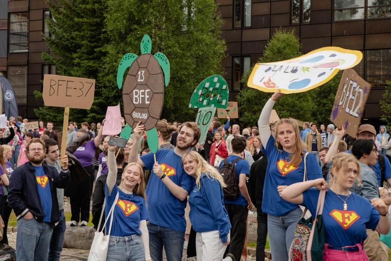 Masse studenter med hjemmelagde plakater p&aring; en campus.
