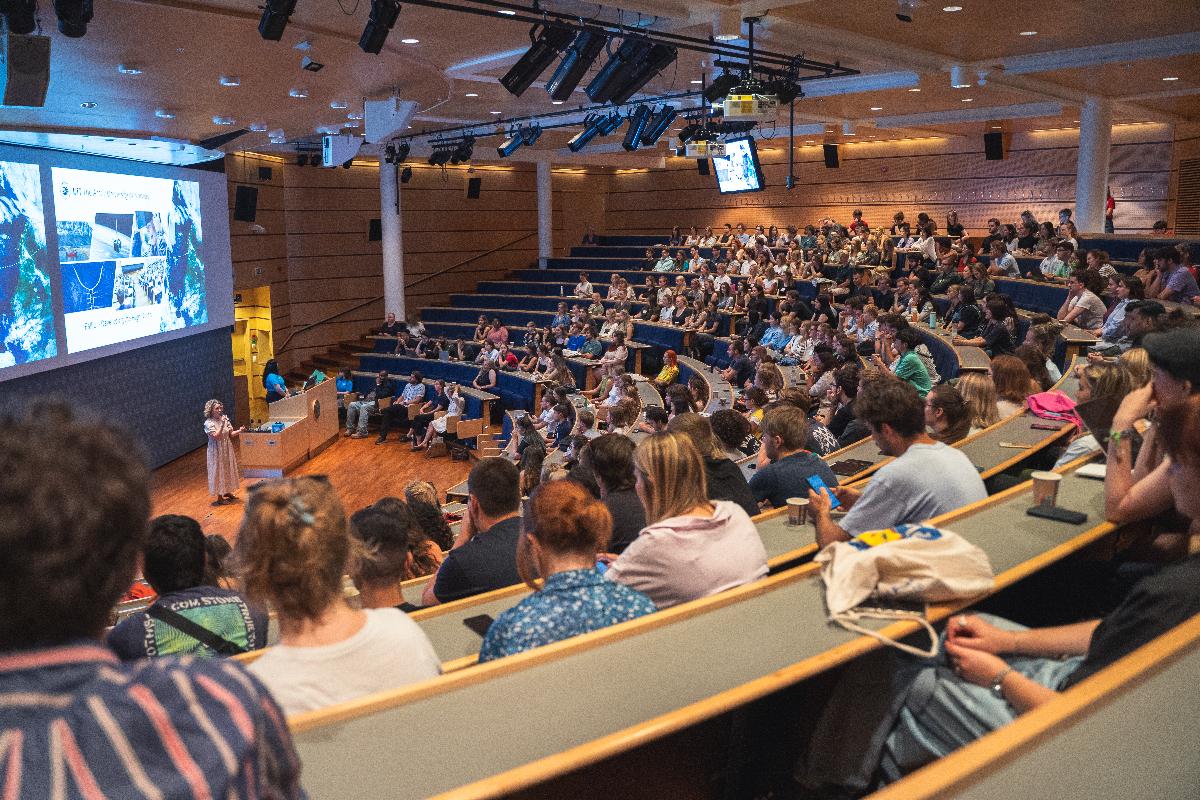 Person som st&aring;r i et audiotorium og taler til et publikum.