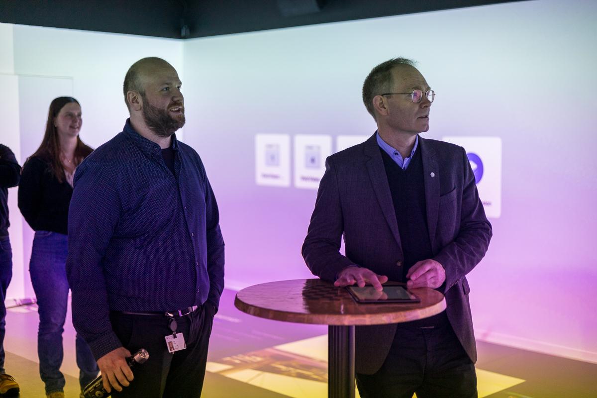 Forsker Marius Wang ved institutt for industriell teknologi (t.v.) lar forsknings- og h&oslash;yere utdannings-minister Oddmund Hoel pr&oslash;ve seg i XR-laben p&aring; UiT Narvik.
