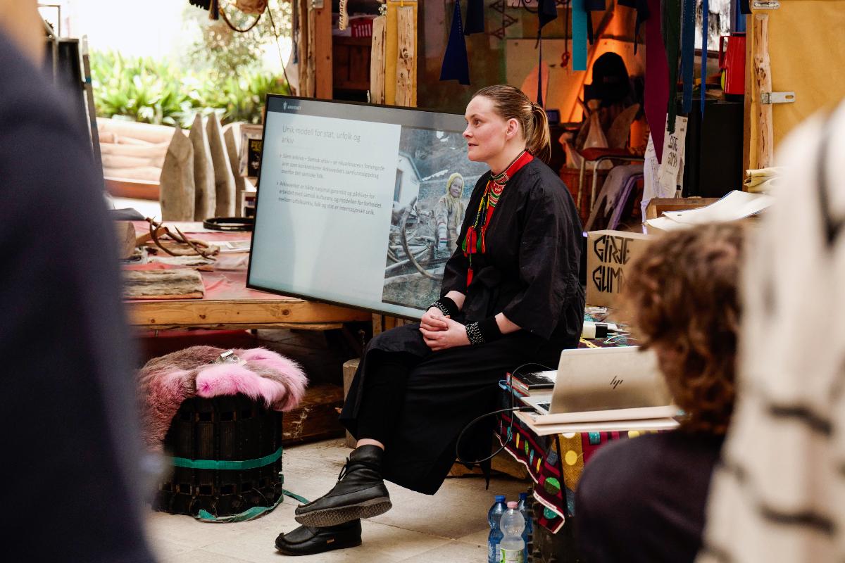 Person sitter p&aring; en scene med publikum rundt seg