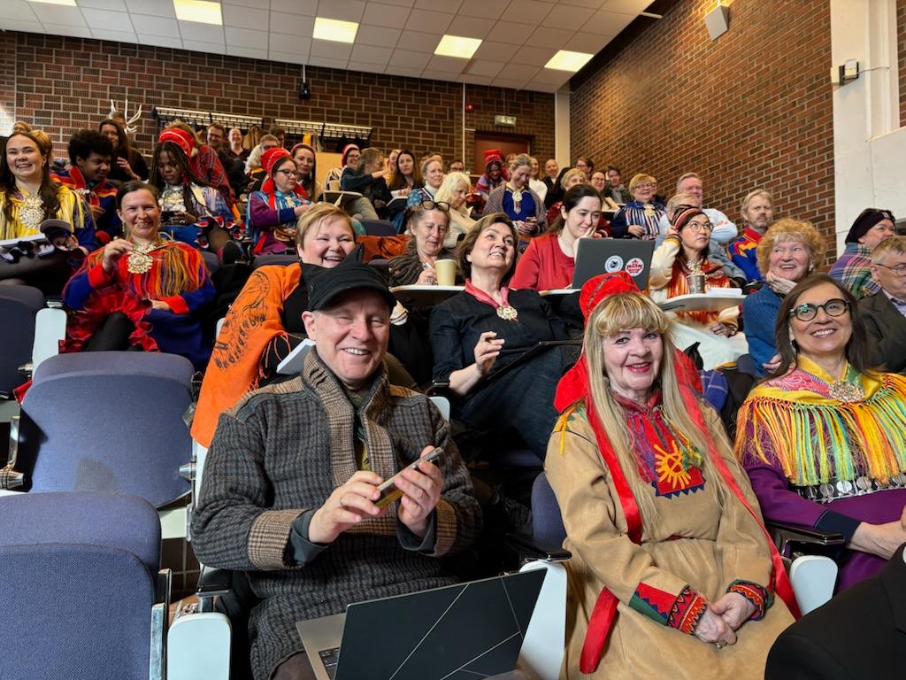 mange folk med kofte i et auditorium