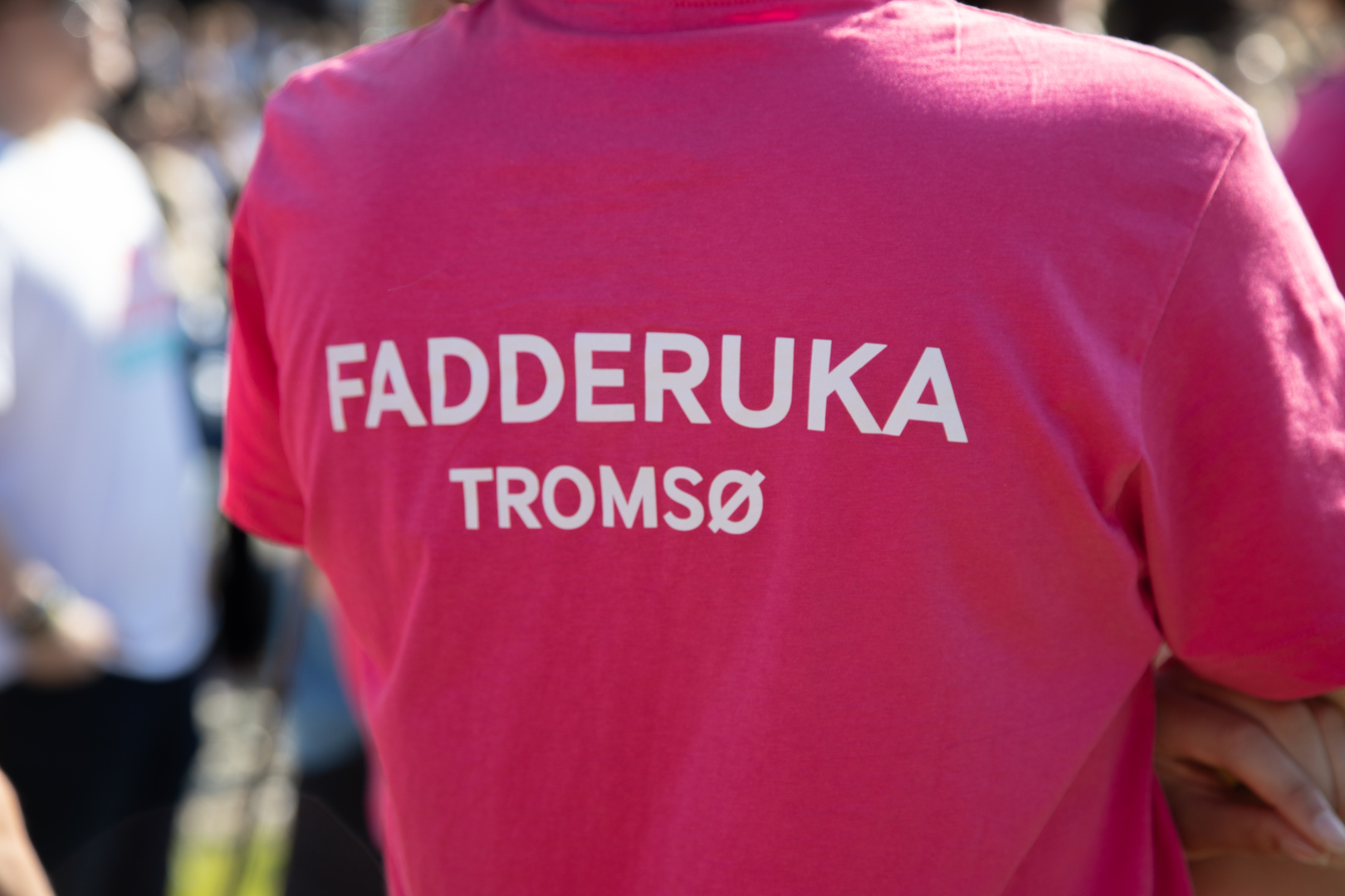 Semesterstart_2024_UIT_25220_Foto_Kaja_Alexandra_Halvei_Larsen.jpg Ryggen til en mann som har på seg en rosa Fadderuke-t-skjorte.