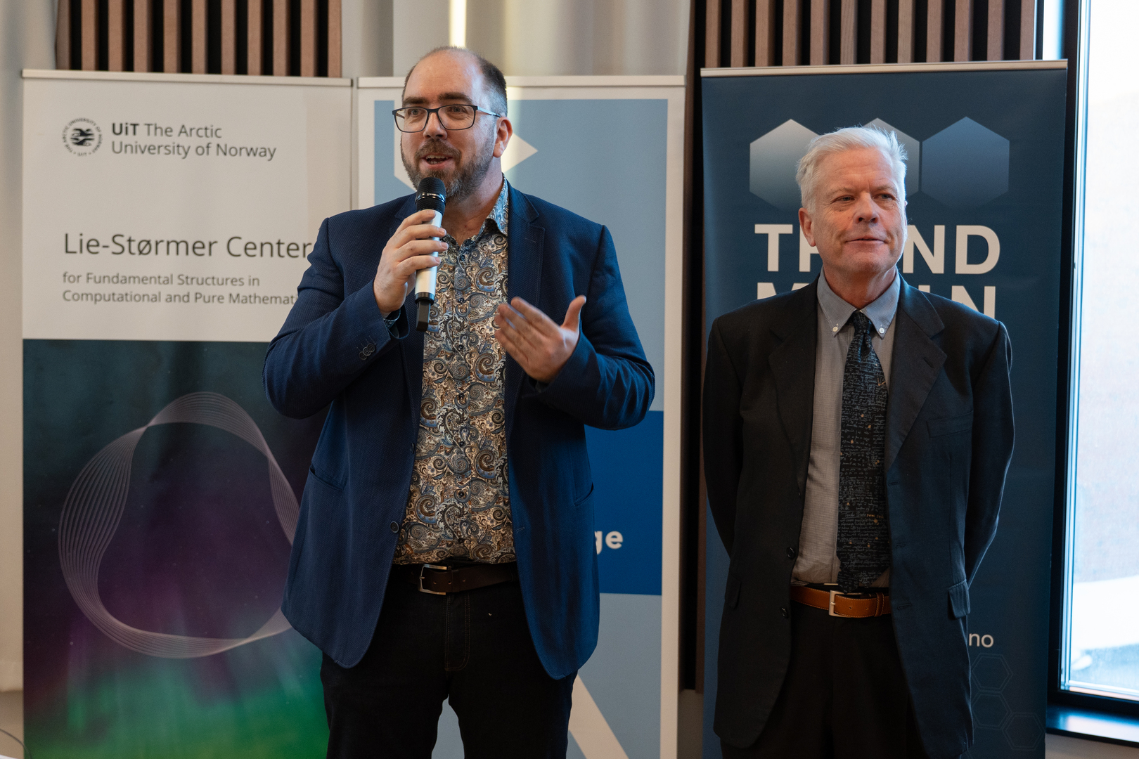 +Cordian+Riener+og+Hans+Munthe-Kaas-09856.jpg to menn som står på en scene, den ene prater i mikrofon