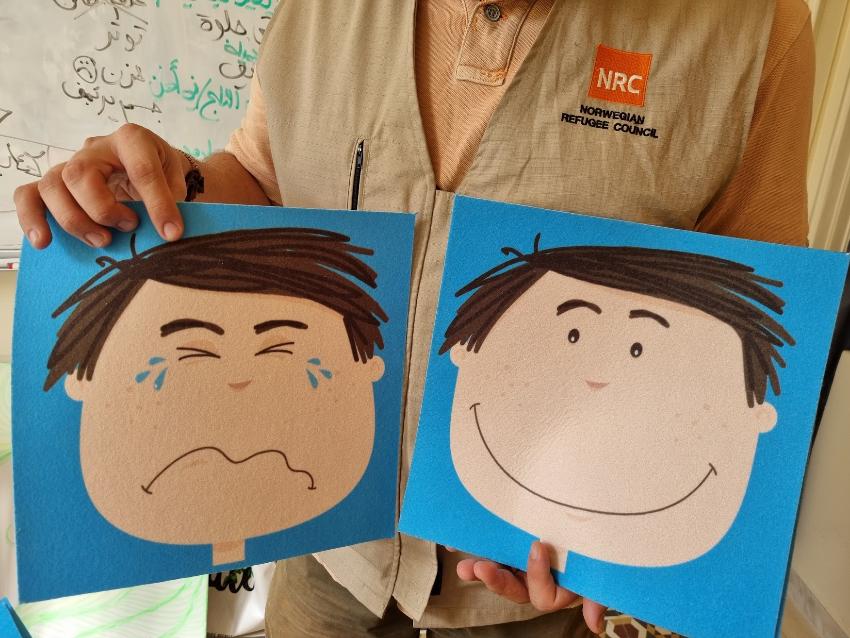 Bildet viser en person som holder to tegninger. Den ene tegningen er av en gutt som gr&aring;ter, og den andre er av en gutt som smiler.