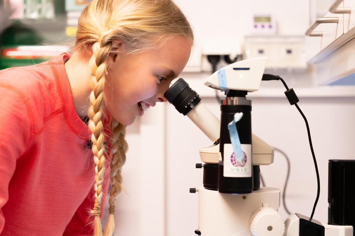 jente som ser i mikroskop