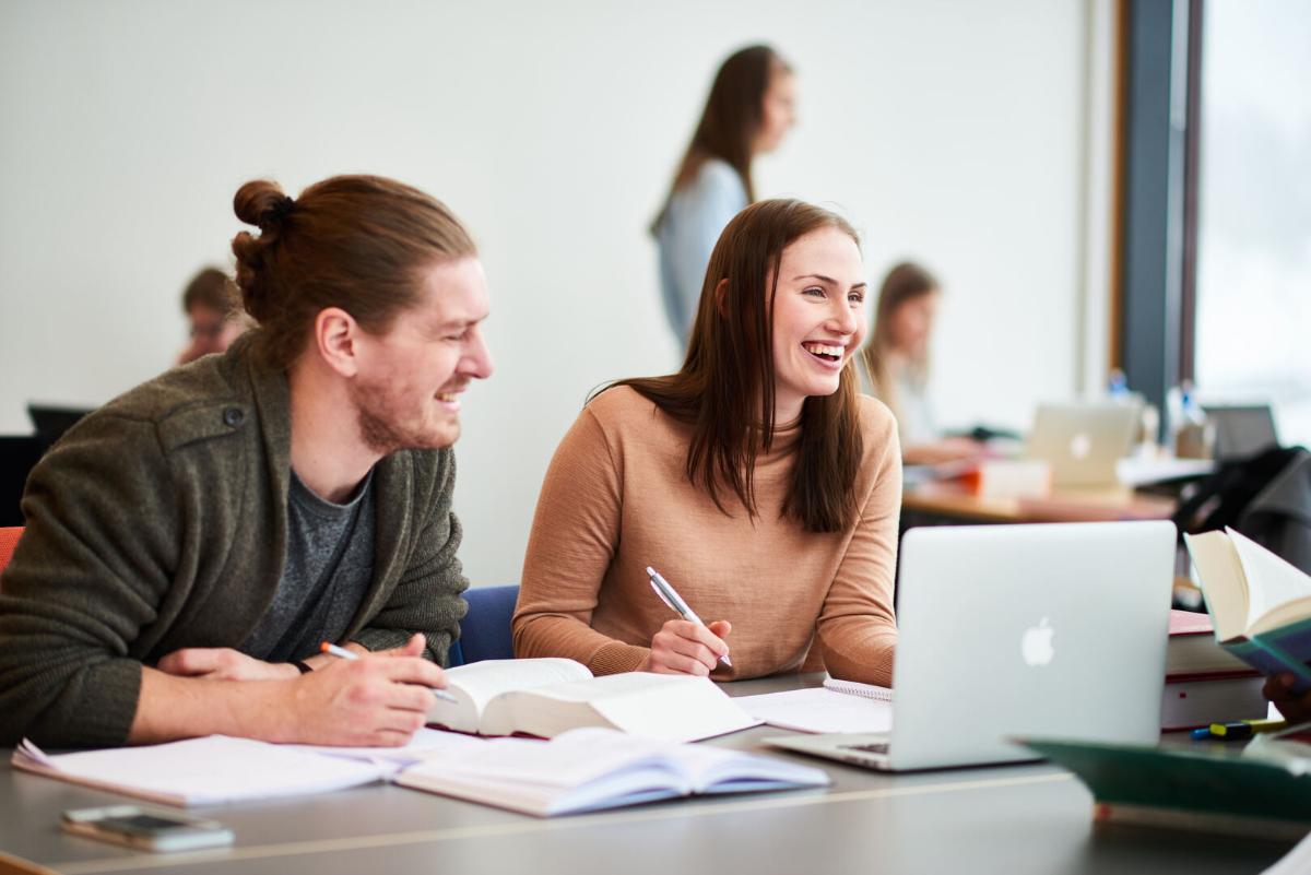Studenter sitter p&aring; pultene sine